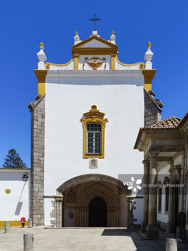 从低角度拍摄的葡萄牙埃武拉一座历史悠久的教堂正面，细节华丽，背景是湛蓝的天空图片素材