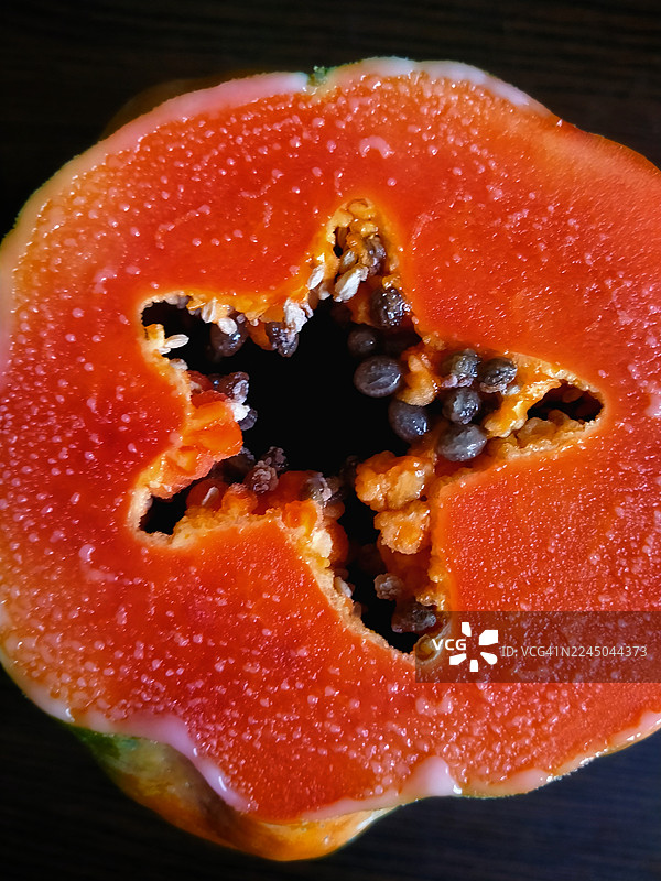 新鲜木瓜近景特写，切开的木瓜展示着饱满的橙色果肉和丰富的籽，质感鲜明图片素材