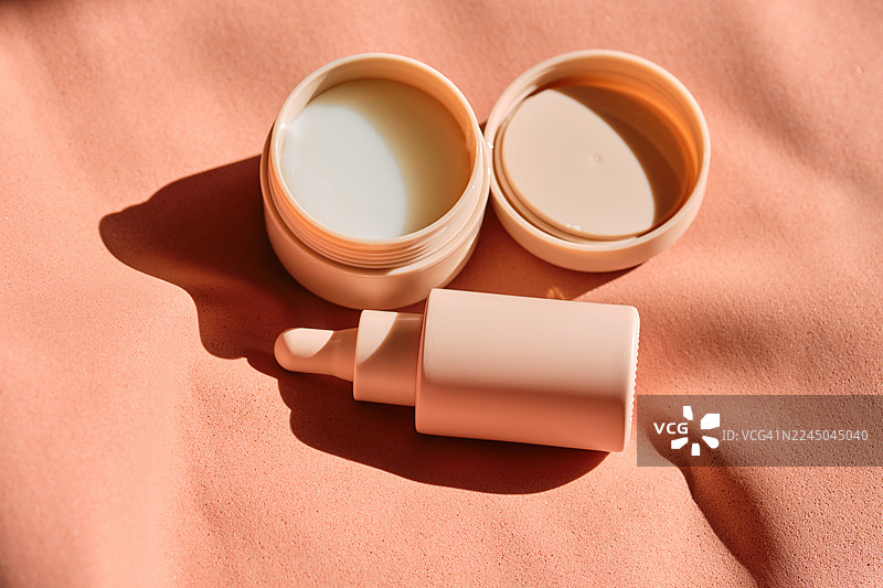 高角度俯瞰，纹理桃色背景上的护肤品，带有阳光和阴影。图片素材