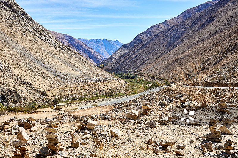 智利埃尔基地区，晴朗蓝天下，干旱山谷中蜿蜒的道路的风景图片素材