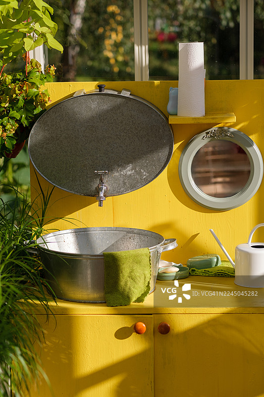带黄色橱柜和镀锌浴缸的户外水槽装置图片素材