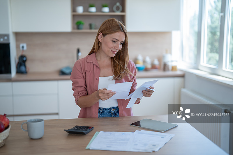 女人在厨房管理家庭账单和财务图片素材