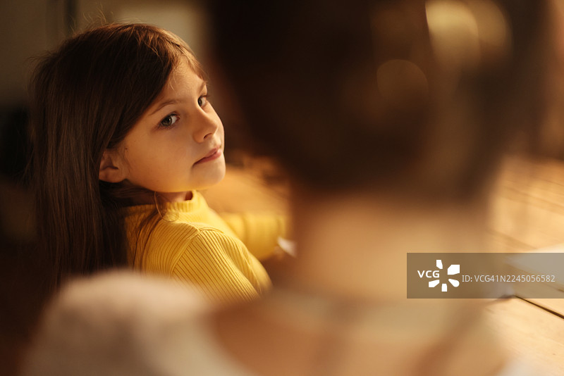 小女孩在做作业时，看着妈妈，脸上带着微笑图片素材