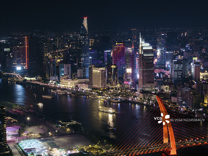 越南胡志明市夜晚充满活力的城市景观，有灯火辉煌的摩天大楼和河景。图片素材