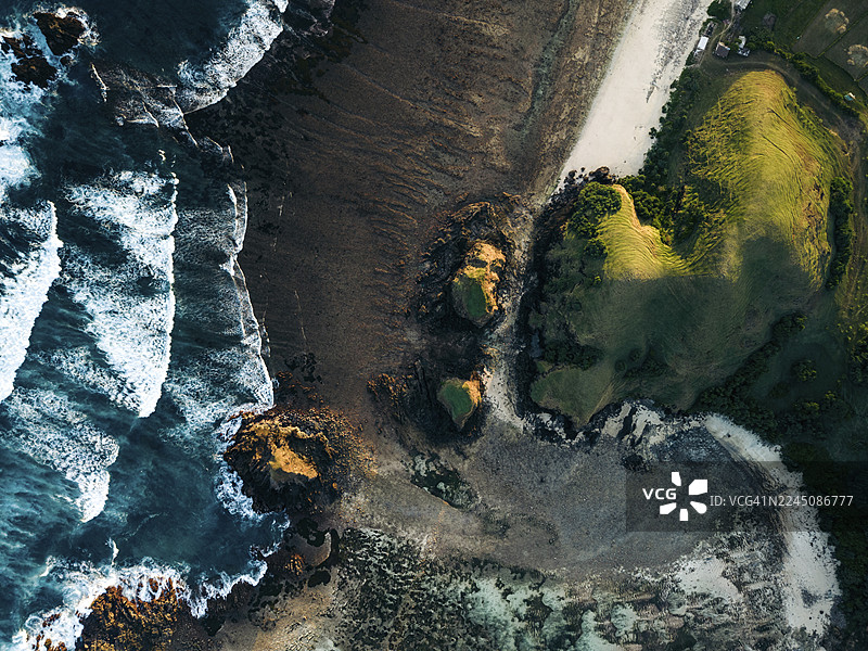 航拍崎岖海岸线，海浪拍打岩石海岸，绿意盎然的山丘。印度尼西亚，东努沙登加拉，中龙目岛摄政区，普聚特区，森科尔，布洛姆格鲁普克海滩图片素材