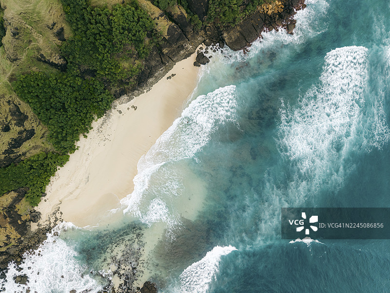 航拍视角下的原始海滩，拥有绿松石色的海浪和郁郁葱葱的绿色悬崖。地点：印度尼西亚，东努沙登加拉，中龙目岛摄政区，巴拉雅镇，马维海滩，塞隆贝拉纳克。图片素材