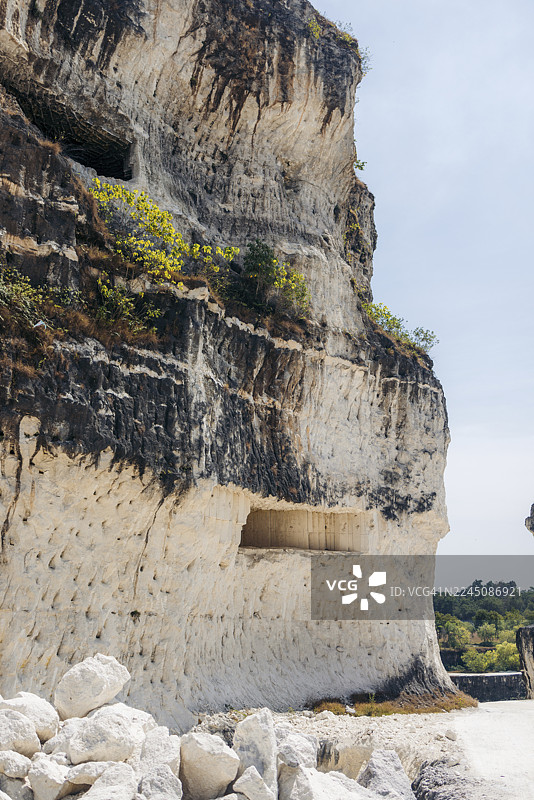 印度尼西亚东爪哇省马都拉岛，晴朗蓝天下拥有天然洞穴的岩石悬崖图片素材
