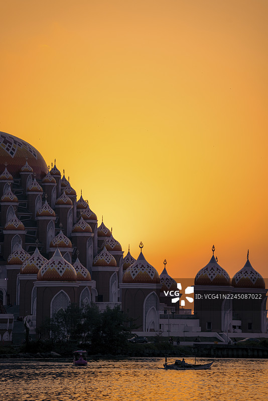 日落时分清真寺的惊艳剪影，橘红色的天空映照在水面上。印度尼西亚，苏拉威西，望加锡图片素材