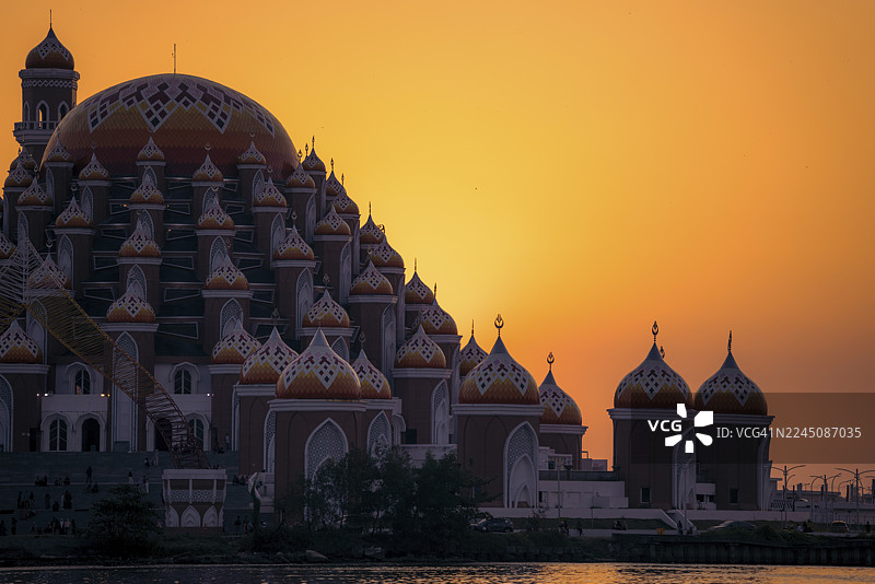 宏伟的清真寺，其华丽的穹顶在充满活力的橙色日落天空中形成剪影。印度尼西亚，苏拉威西，望加锡图片素材