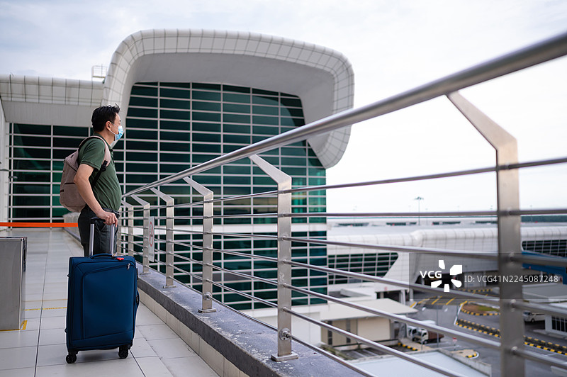 一名亚洲男性旅客在机场航站楼侧身等待航班图片素材