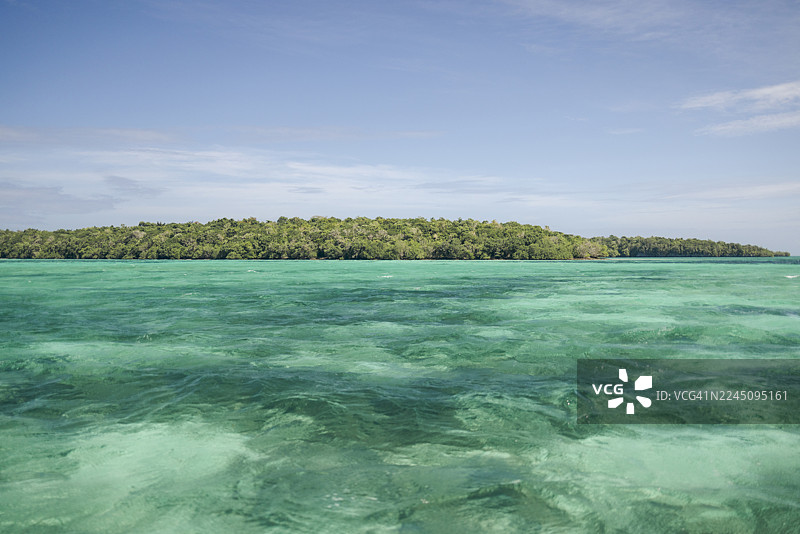 蓝天下的碧绿海水环绕着郁郁葱葱的绿色森林的热带岛屿。印度尼西亚马鲁古省东南马鲁古县的小凯伊岛的拜尔岛或拜尔岛。图片素材