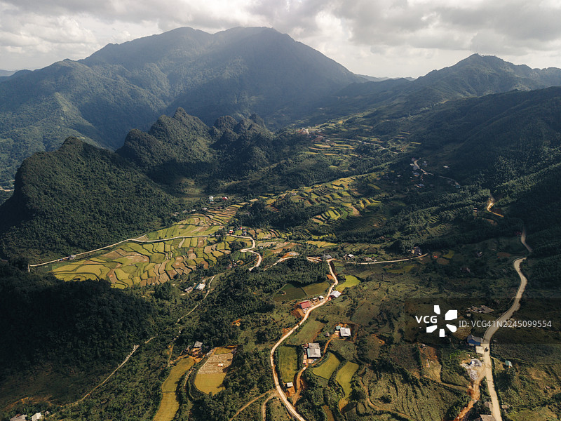 越南高平省和平县，郁郁葱葱的山谷空中俯瞰图，梯田环绕着群山和蜿蜒的道路。图片素材