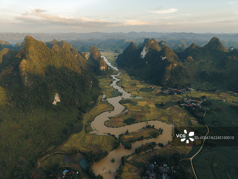 日落时分，空中俯瞰蜿蜒的河流穿过郁郁葱葱的绿色山谷和崎岖的山地景观。越南高平省重庆县丰南。图片素材