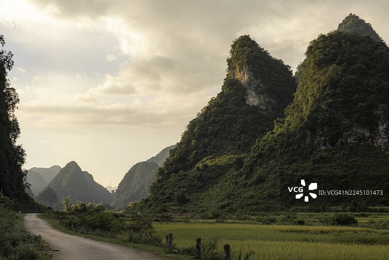 宁静的风景，有郁郁葱葱的绿山和蜿蜒的道路，天空布满云彩。越南高平省重庆县丰南图片素材