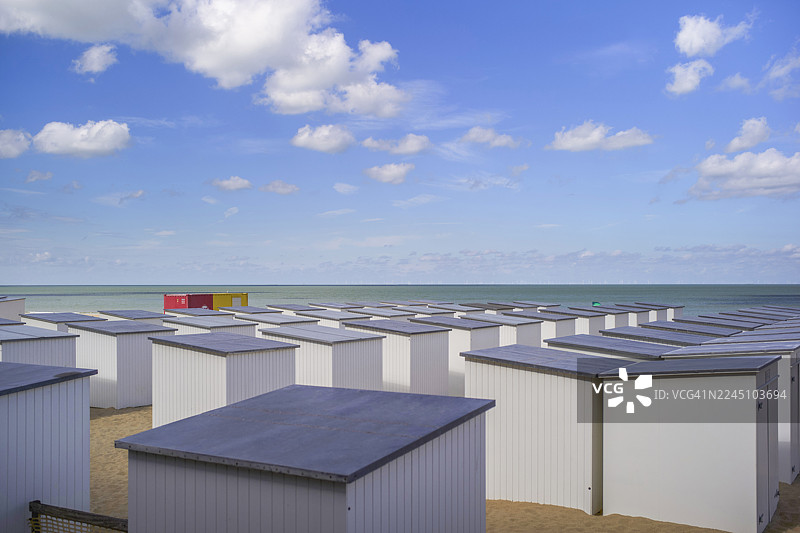 蓝天白云下的海边，一排排白色海滨小屋，灰色屋顶。比利时西弗兰德省布兰肯贝赫。图片素材