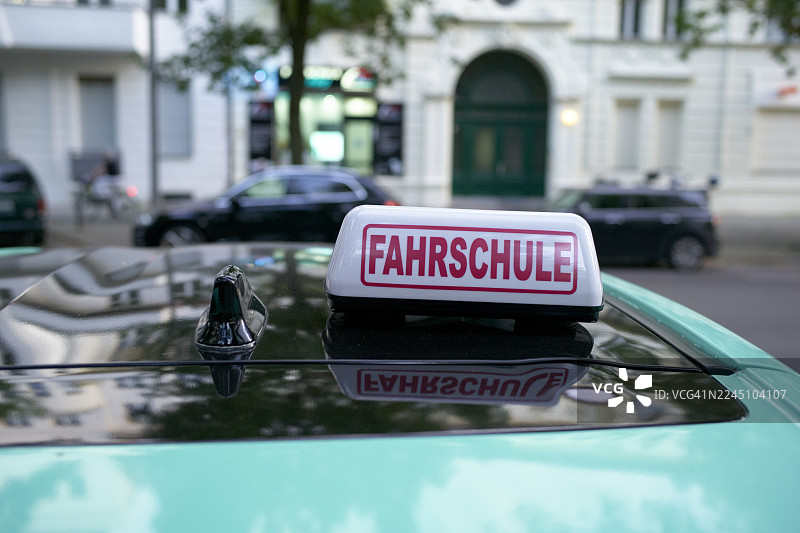 一辆车顶上带有驾驶学校标志的汽车，背景是城市建筑。德国柏林图片素材