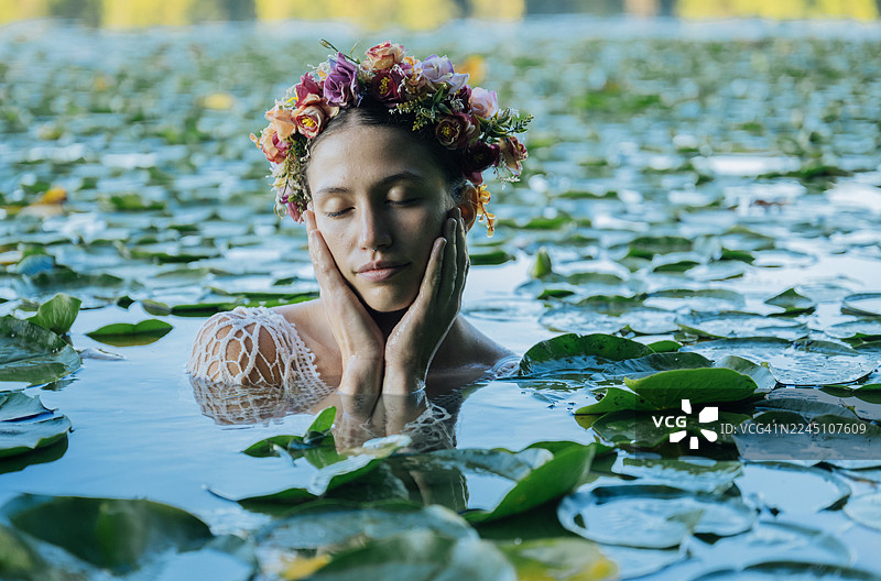 一位戴着花冠的女子在睡莲中安详漂浮，闭着双眼。地点：美国华盛顿州野猫湖公园。图片素材