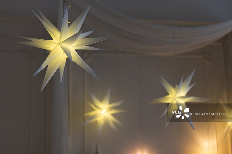 昏暗的房间里，天花板上悬挂着发光的纸质星星，进行着装饰。图片素材