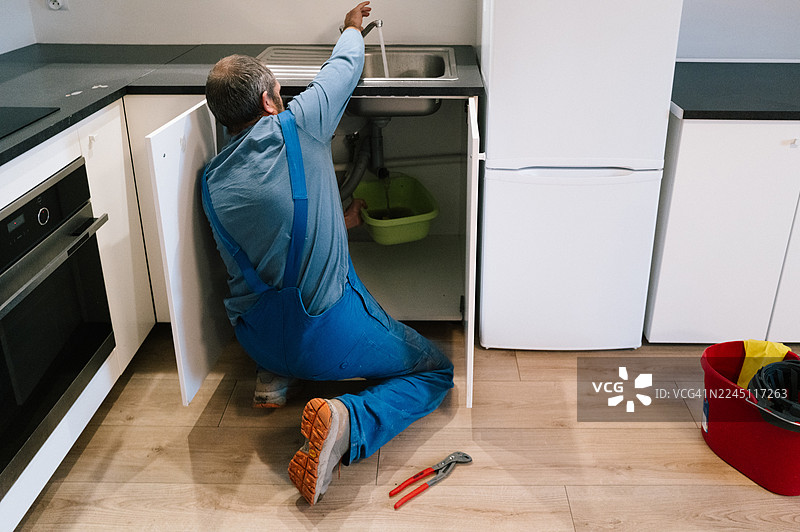 一位水管工正在修理厨房堵塞的排水管图片素材