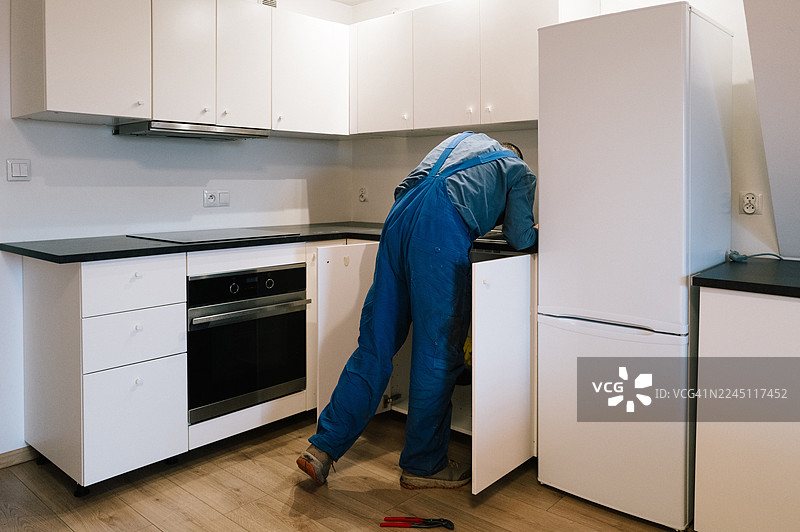 一位水管工正在修理厨房堵塞的排水管图片素材