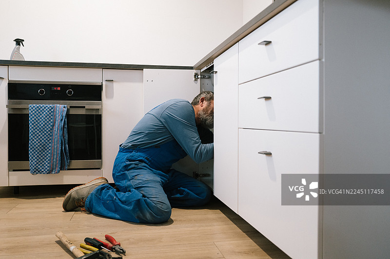 水管工正在修理厨房堵塞的排水管图片素材