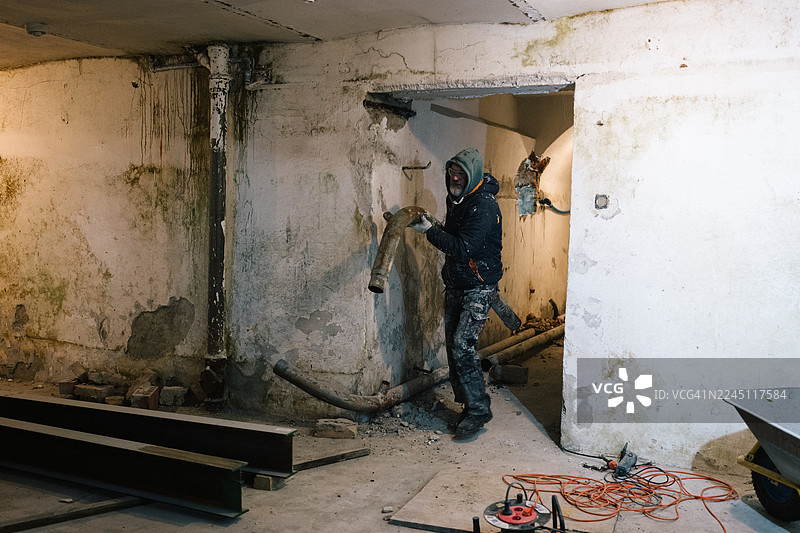 一名建筑工人正在搬运拆除下来的旧水管图片素材