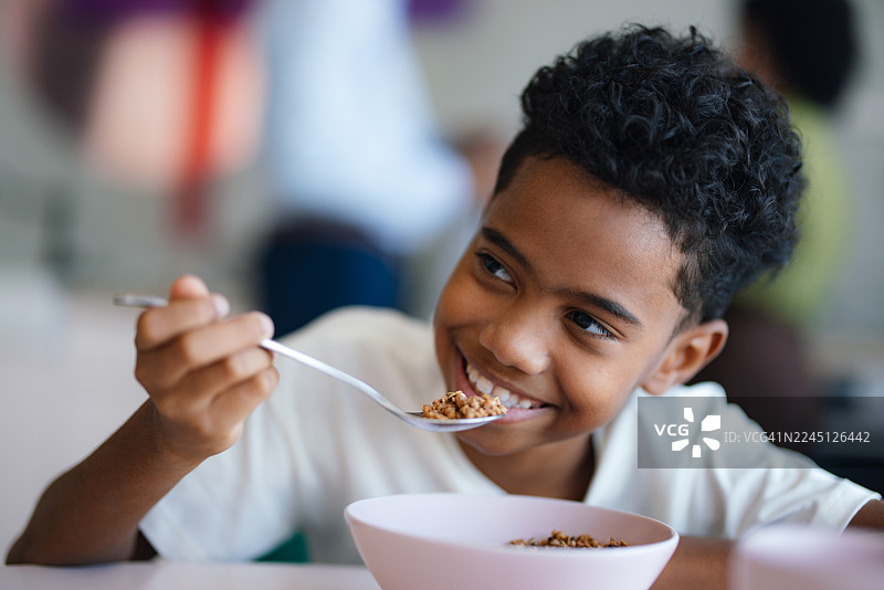 快乐的小男孩在舒适的公寓厨房里享用谷物早餐图片素材