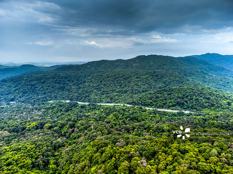 从马哈拉施特拉邦潘韦尔附近的卡纳拉鸟类保护区俯瞰郁郁葱葱的西高止山脉。蜿蜒的道路穿过季风云下的茂密森林，展示了萨雅德里山脉丰富的生物多样性和自然美景。图片素材