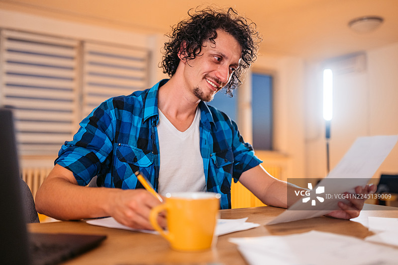 中年男子在家里的厨房餐桌上查看财务状况图片素材
