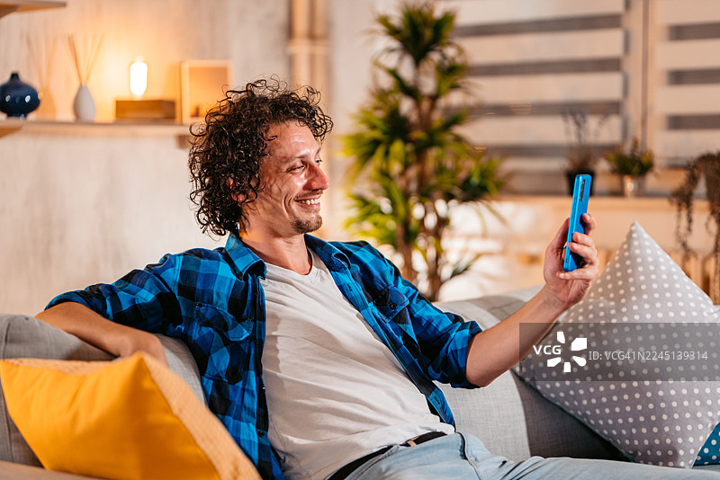 中年男子在家中通过手机与朋友进行视频通话图片素材