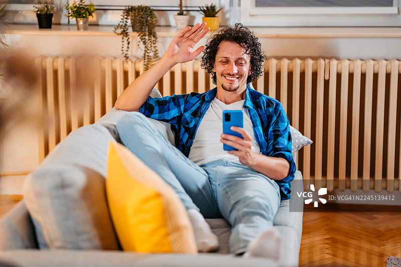 中年男子在家中坐着，通过手机与朋友进行视频通话图片素材