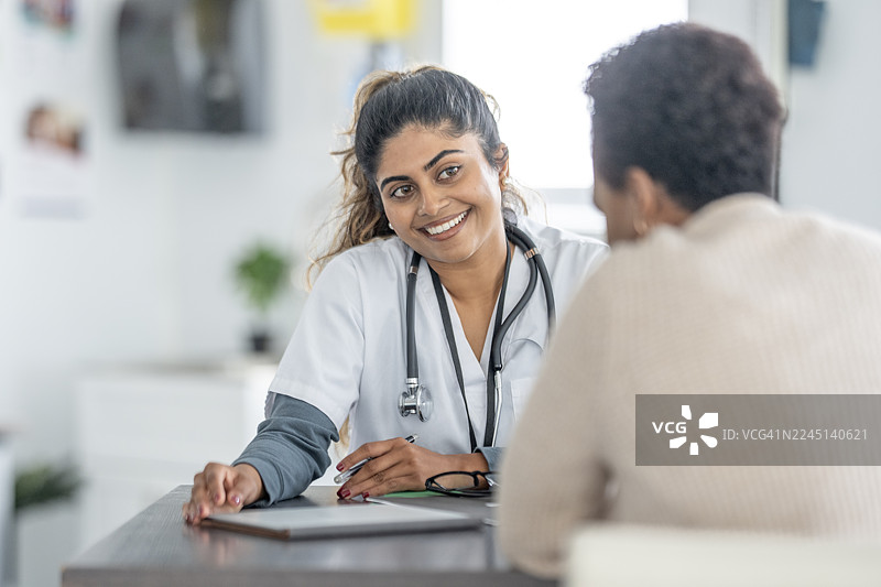 南亚医生在诊所内听诊并咨询病人，友好的医疗咨询图片素材