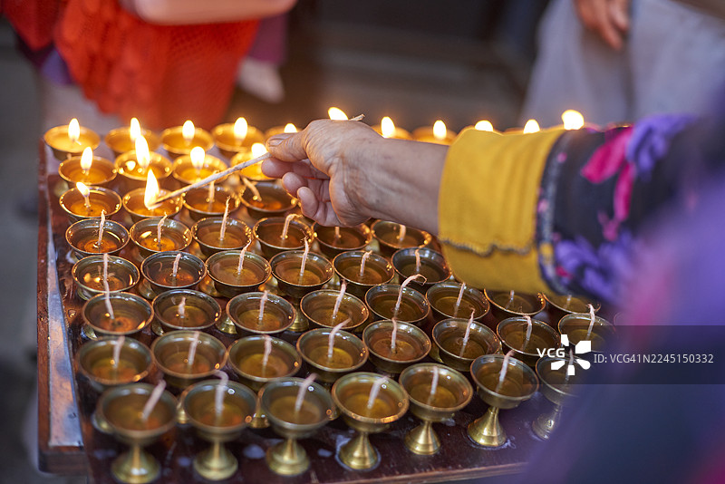 尼泊尔手工点亮一排排传统的酥油灯图片素材