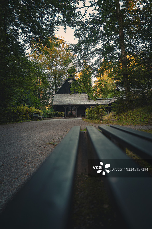 森林中的小型木制教堂，傍晚时分，周围环境昏暗，富有氛围感。德国卡尔夫县阿尔滕施泰格。图片素材
