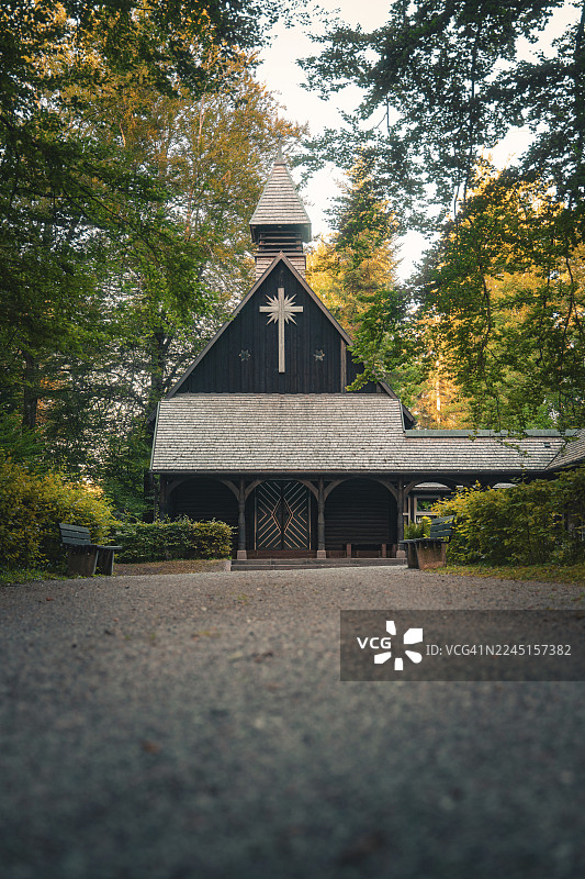 森林中的木制教堂，周围环绕着树木，营造出富有氛围的夜晚景象，德国卡尔夫区阿尔滕施泰格图片素材