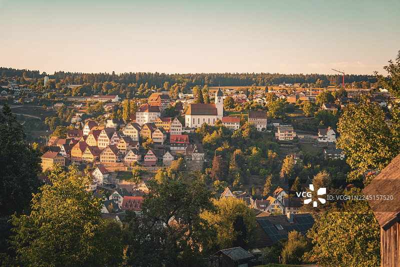 德国卡尔夫区阿尔滕施泰格村庄，位于山丘之上，中间有显眼的教堂，光线温暖，树木繁茂。图片素材