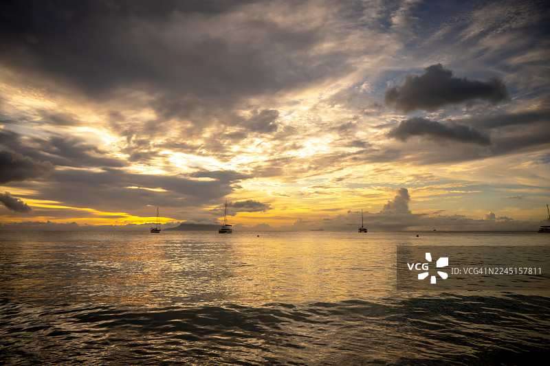 塞舌尔博瓦隆海滩，日落时分色彩斑斓的天空下，海岸景观与船只剪影图片素材