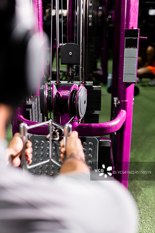 男人在健身房器械上训练，锻炼肌肉力量图片素材