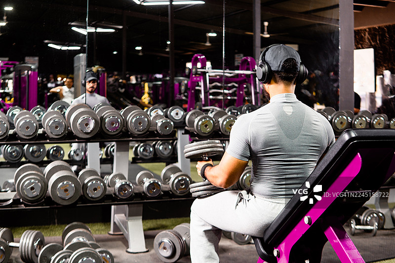 男人在健身房举哑铃锻炼，享受健身过程图片素材