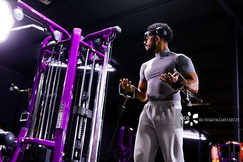 男子在健身房使用配有科技设备的绳索训练器进行训练图片素材