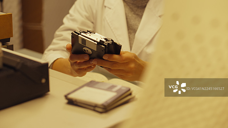 老式科学研究实验室。女科学家正在整理装有研究数据的软盘图片素材