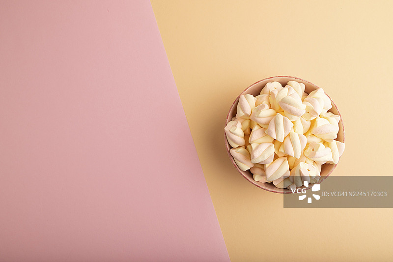 橙粉色棉花糖装在陶瓷碗里，背景为粉橙色纸张，俯视，平面布置，可留白，极简风格图片素材