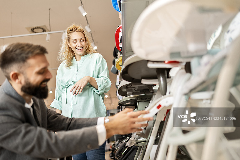 年轻的家庭在商店过道里挑选婴儿旅行推车图片素材