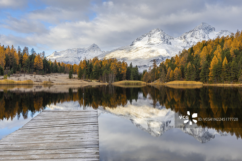 秋季,雪山环绕的斯塔泽湖,混交林(落叶松),木栈道,倒影,阿尔布纳峰,朱利尔峰,奈尔峰,波拉斯钦峰,塞勒里纳/施拉里尼亚,恩加丁,格劳宾登,瑞士图片素材