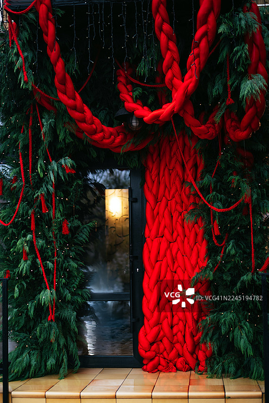 玻璃建筑的商店外墙装饰着圣诞装饰品和圣诞树，门槛也装饰着新年饰品，整个房屋都充满了节日气氛。图片素材