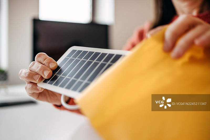 一位女士坐在小型家庭仓库里，在线销售商品并打包图片素材