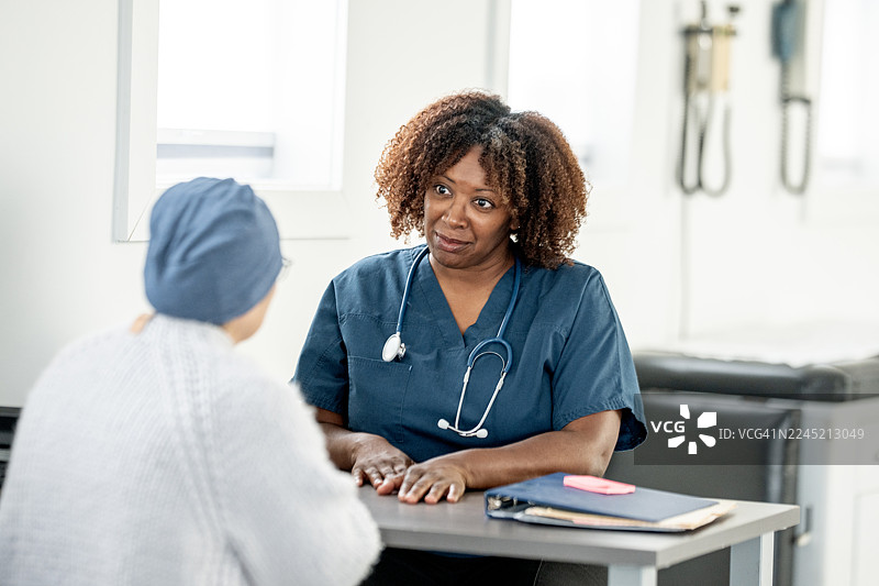 今日，一位黑人女护士在诊所前台为病人提供医疗咨询和关怀支持图片素材