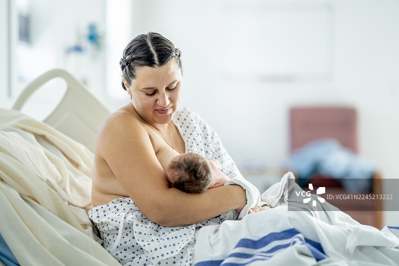 西班牙裔母亲在住院期间哺乳新生儿：产后温柔的亲子时光，产后护理图片素材