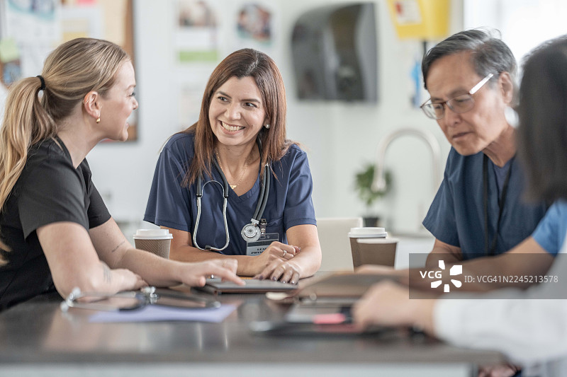 多样化的医疗团队在诊所会议上围坐在一张桌子旁，为患者护理进行协作图片素材