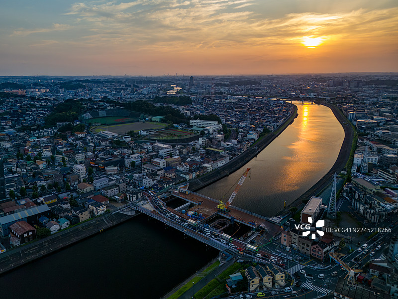 正在进行主要的桥梁更换工程。日落映照在河面上。一座横跨河流的桥梁。鹤见川的无人机航拍。西边是横滨市鹤见区；东边是川崎市川崎区和幸区。图片素材